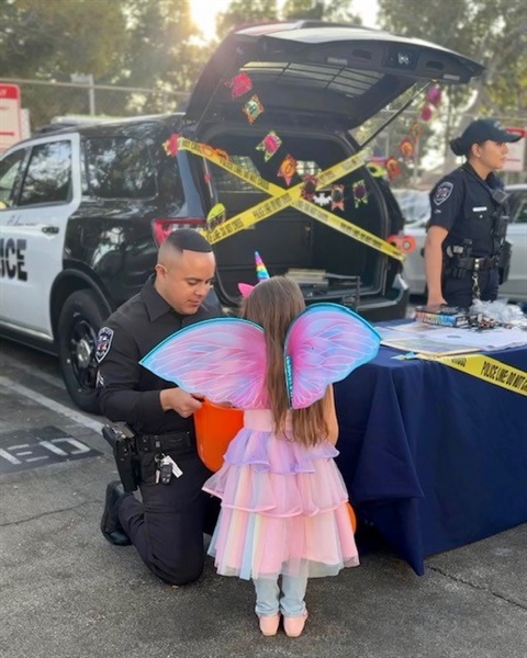 Police officer kneeling down to talk to a child in a halloween costume