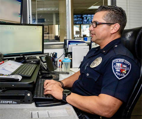 police officer typing on a computer keyboard in an office